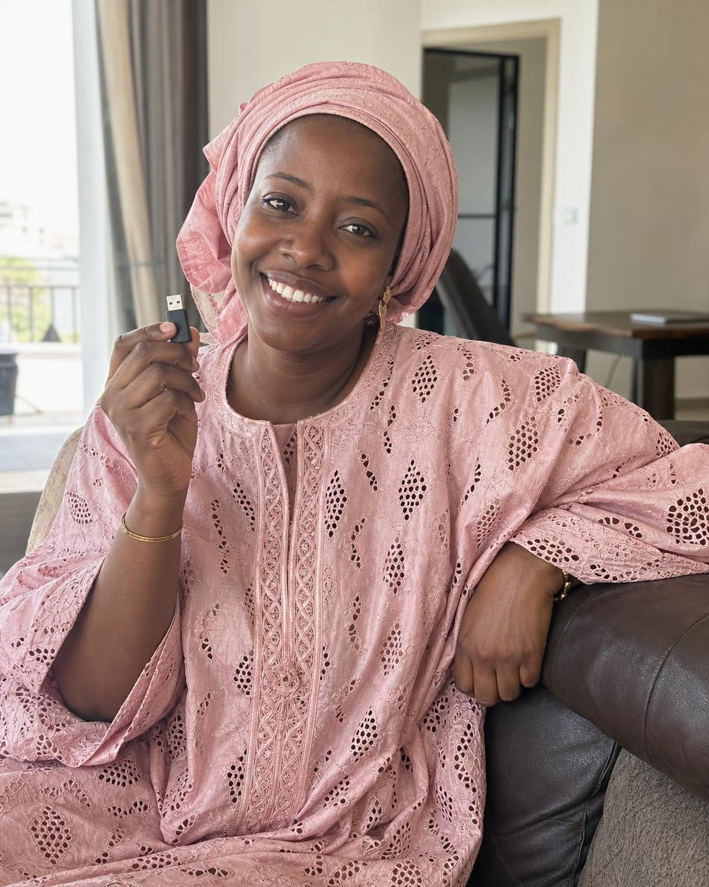 Cliente sénégalaise satisfaite tenant sa clé USB Coran ALINEA 221